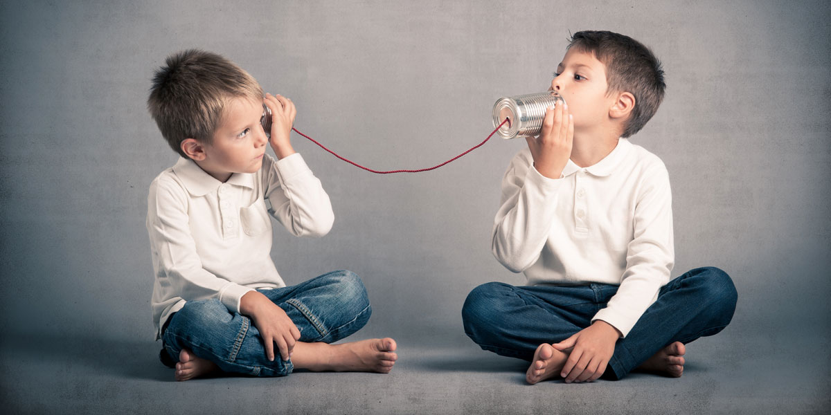 Two young boys using tin can and string telephone