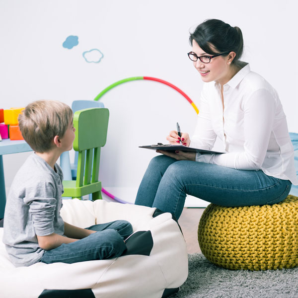 Female counsellor talking to child in playroom